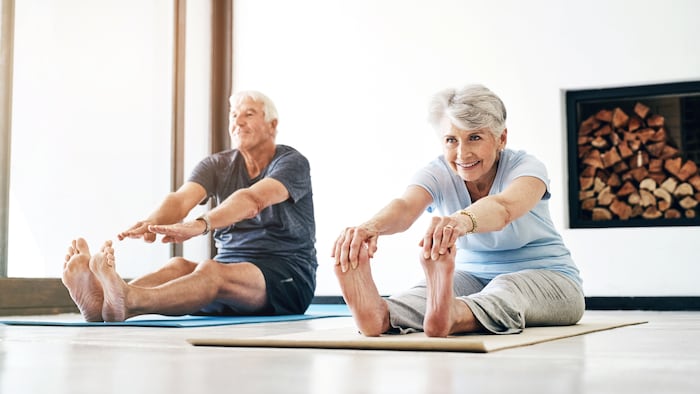 Two senior citizens trying to touch their toes.
