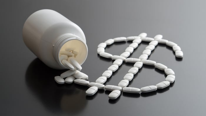 Medical business or prices concept. Making money in pharmaceutical industry or high medical expenses. Also drug dealing, dealer or trade. Dollar sign written with pills spilled from a medicine bottle.