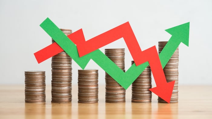 Stack of coins with red and green graph arrows pointing up and down
