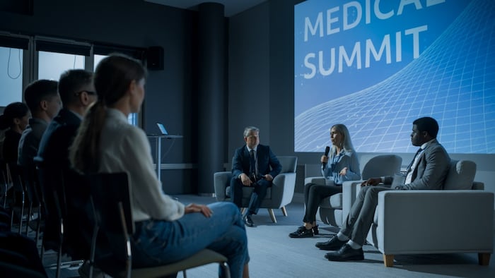 International Medical Summit: Host Asking Caucasian Female Pharmaceutical CEO a Question In Front Of Audience Of Diverse Attendees. Woman Talking About New Developments In Biotechnology, Medicine.