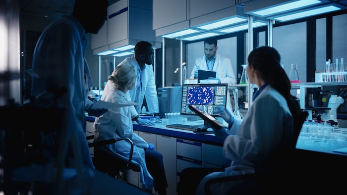scientists gathered around a computer analyzing research